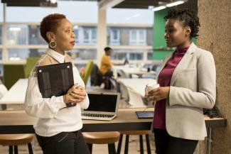 two women standing next to each other in front of a laptop by UK Black Tech courtesy of Unsplash.