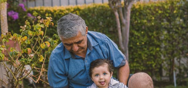 man in blue button up shirt carrying baby in black and white stripe shirt by Alvaro Reyes courtesy of Unsplash.