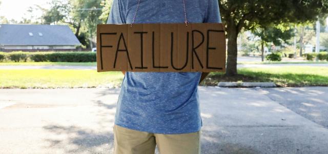 man in blue and white crew neck t-shirt holding brown wooden signage by Mick Haupt courtesy of Unsplash.